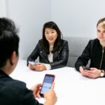 three people in a meeting wearing black jacket holding phones